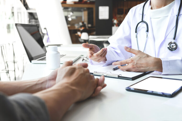 Midsection Of Doctor Consulting Patient At Hospital