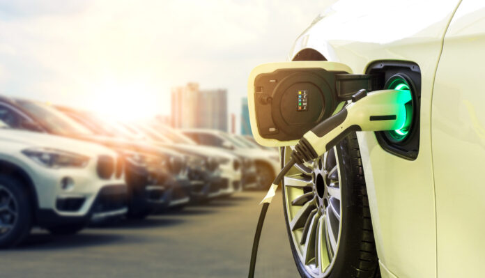 Power supply connect to electric car for add charge to the battery. Charging re technology industry transport which are the future of the Automobile with city background.